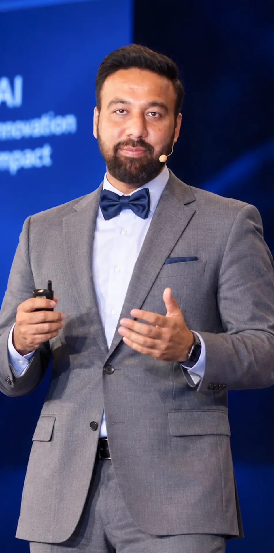 Ahmed Abdullah speaking on stage with a presentation remote